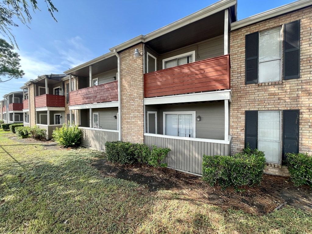 a row of apartment buildings with a grassy area in front of them  at The Alara, Texas