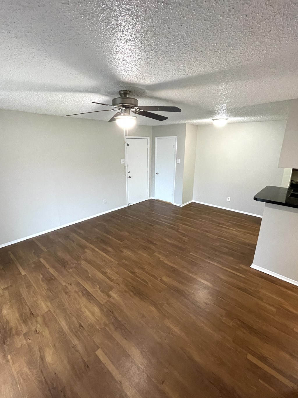 an empty living room with wood floors and a ceiling fan