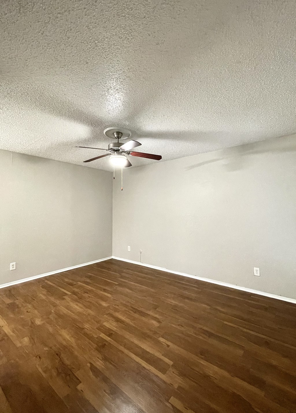 an empty living room with wood flooring and a ceiling fan