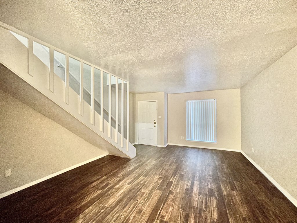the living room and dining room of a house with wood flooring and a staircase
