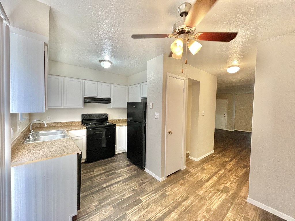 the view of a kitchen and living room with a ceiling fan