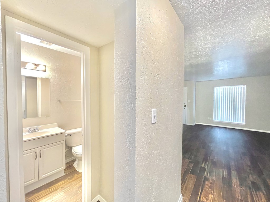 an empty living room and bathroom with hardwood flooring