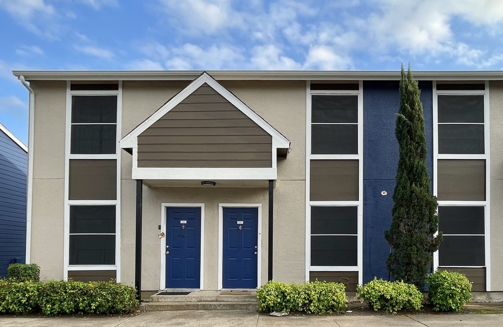 a building with two blue doors and a tree in front of it