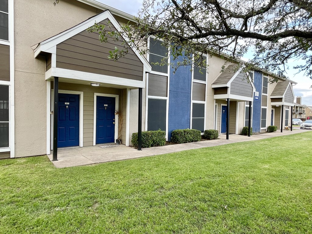 a row of townhomes with blue doors and green grass