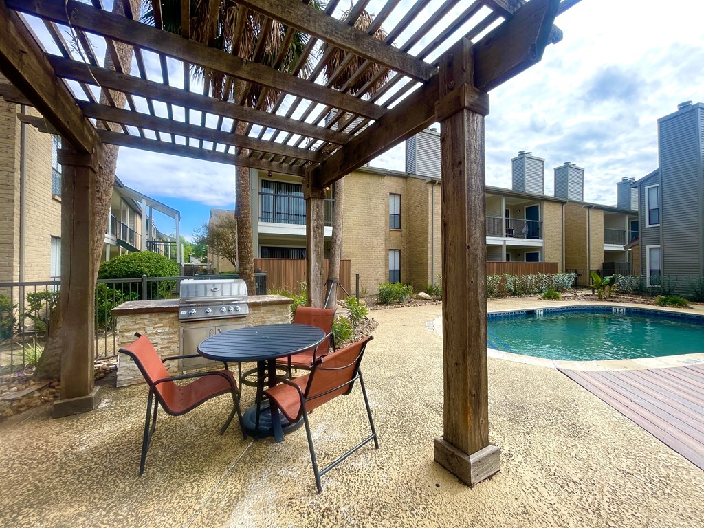 a patio with a table and chairs next to a pool at Oaks of Westchase, Texas