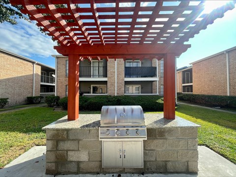 Outdoor grilling area with pergola and brick barbecue at The Alara Apartments, Texas