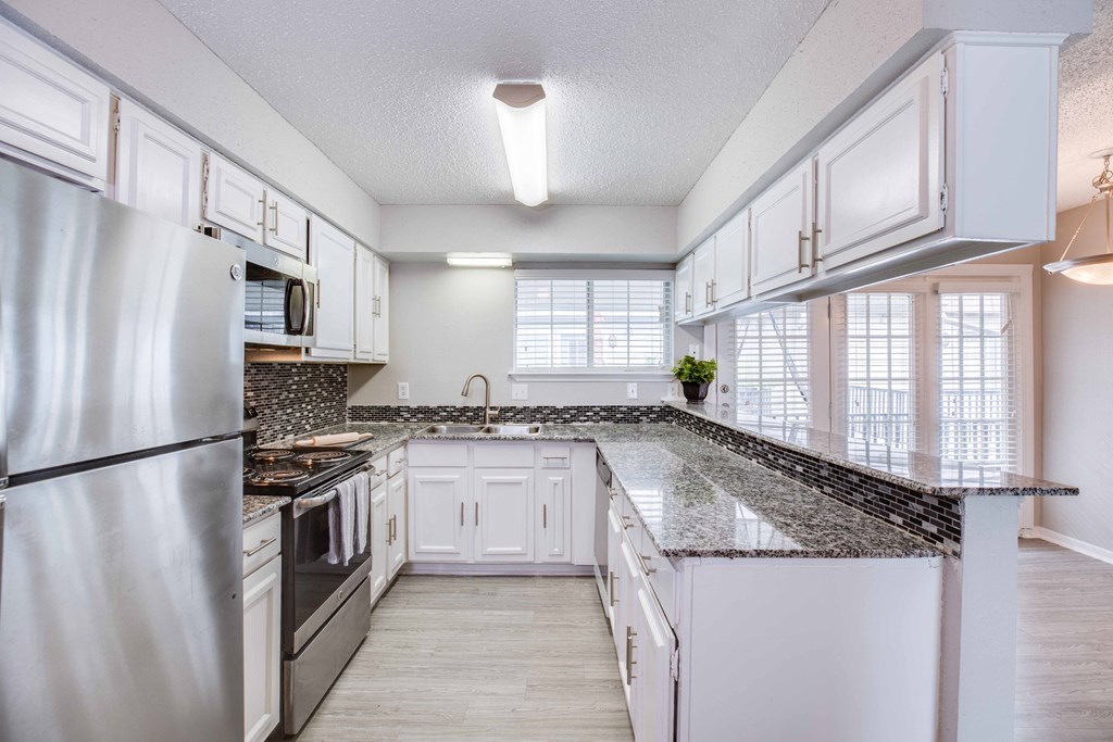 A kitchen with white cabinets and a granite countertop.