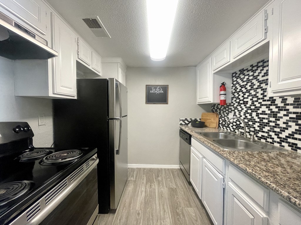 a kitchen with white cabinets and black appliances  at 2151 Kirkwood, Texas