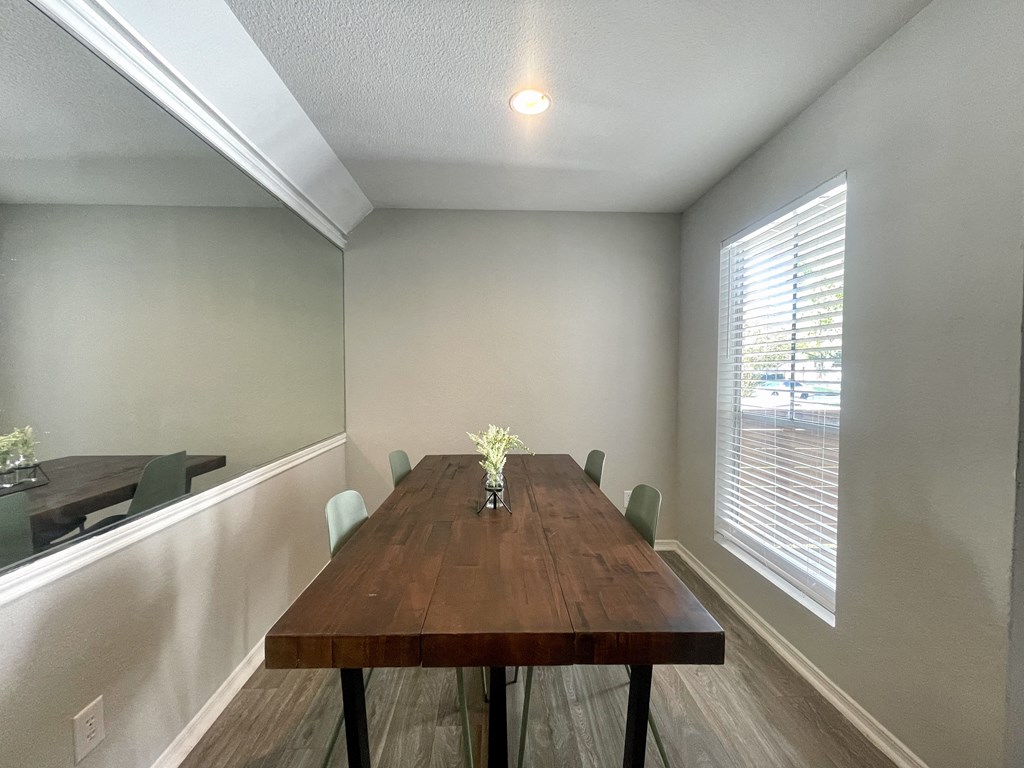 a dining room with a long wooden table and a large window  at 2151 Kirkwood, Houston, 77077