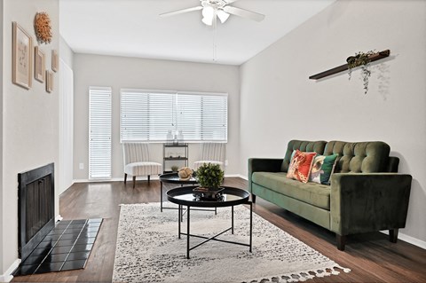 Living room with green sofa and fireplace at Augusta Court Apartments, Houston