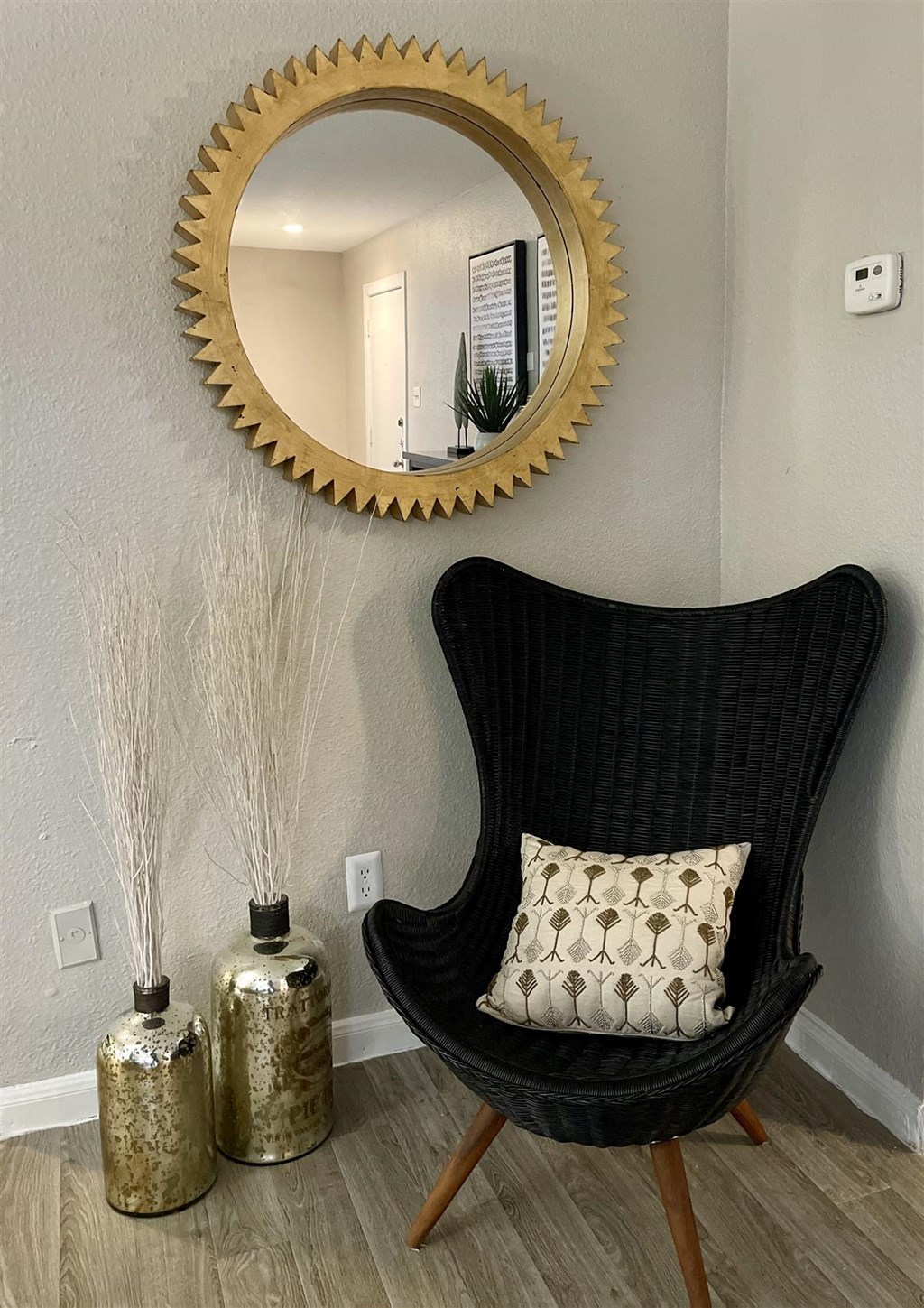 a chair with a pillow and a mirror on the wall