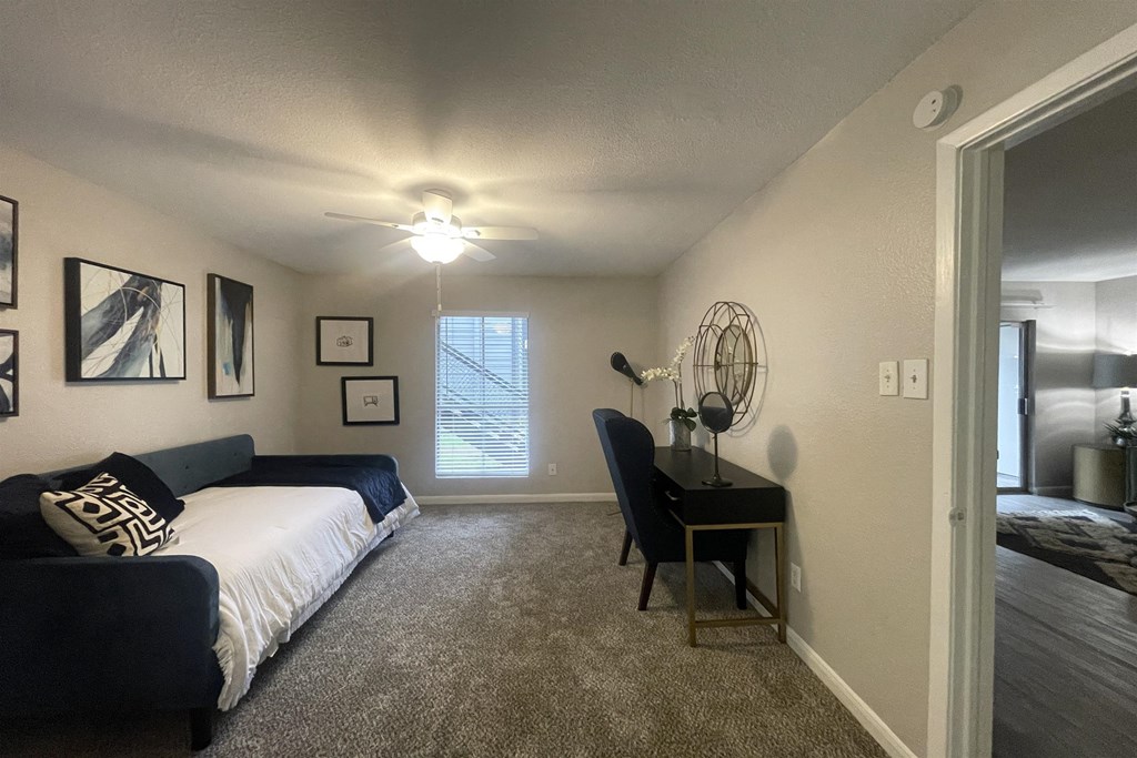 a bedroom with a bed and a desk and a ceiling fan