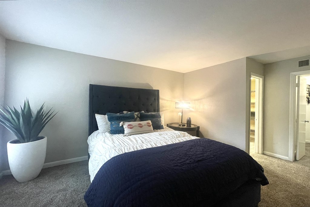 a bedroom with a large bed and a potted plant
