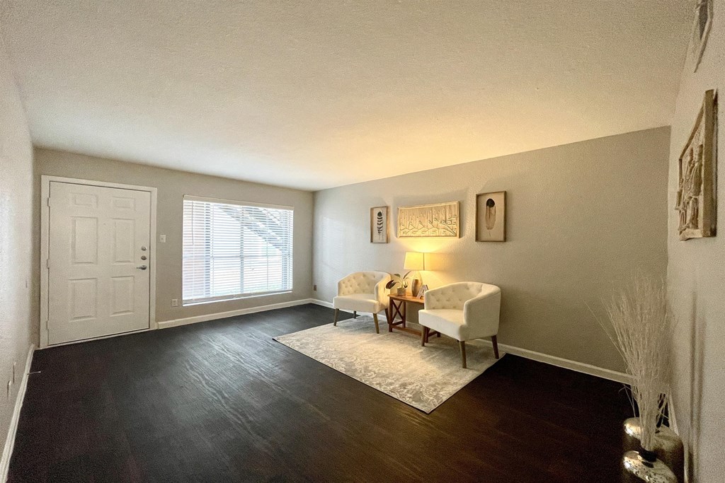 an empty living room with two chairs and a table