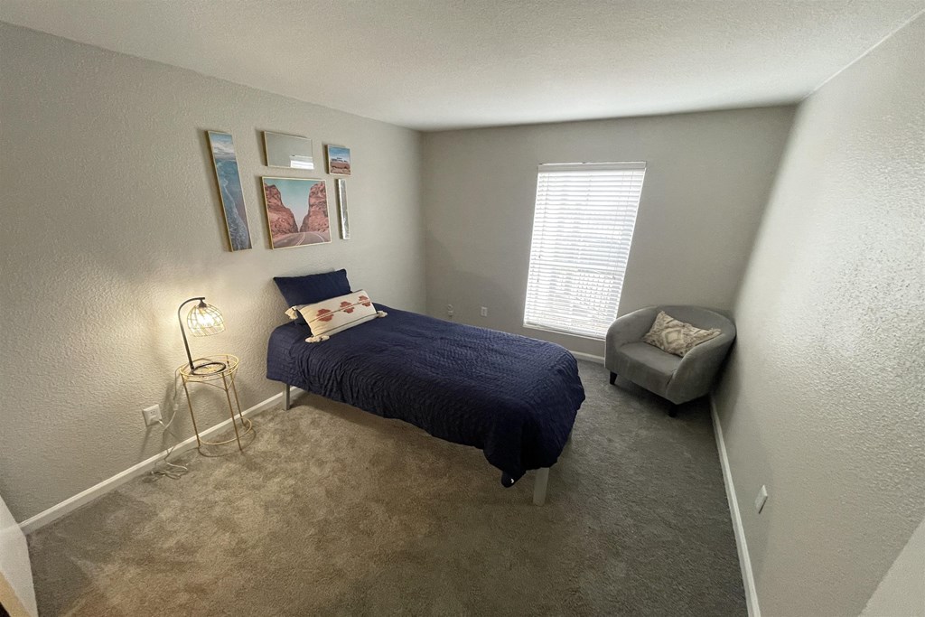 a bedroom with a bed and a chair and a window