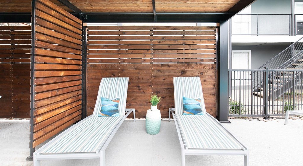 a pair of wooden benches with pillows on a patio