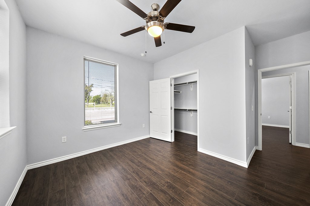 an empty living room with a ceiling fan and a window