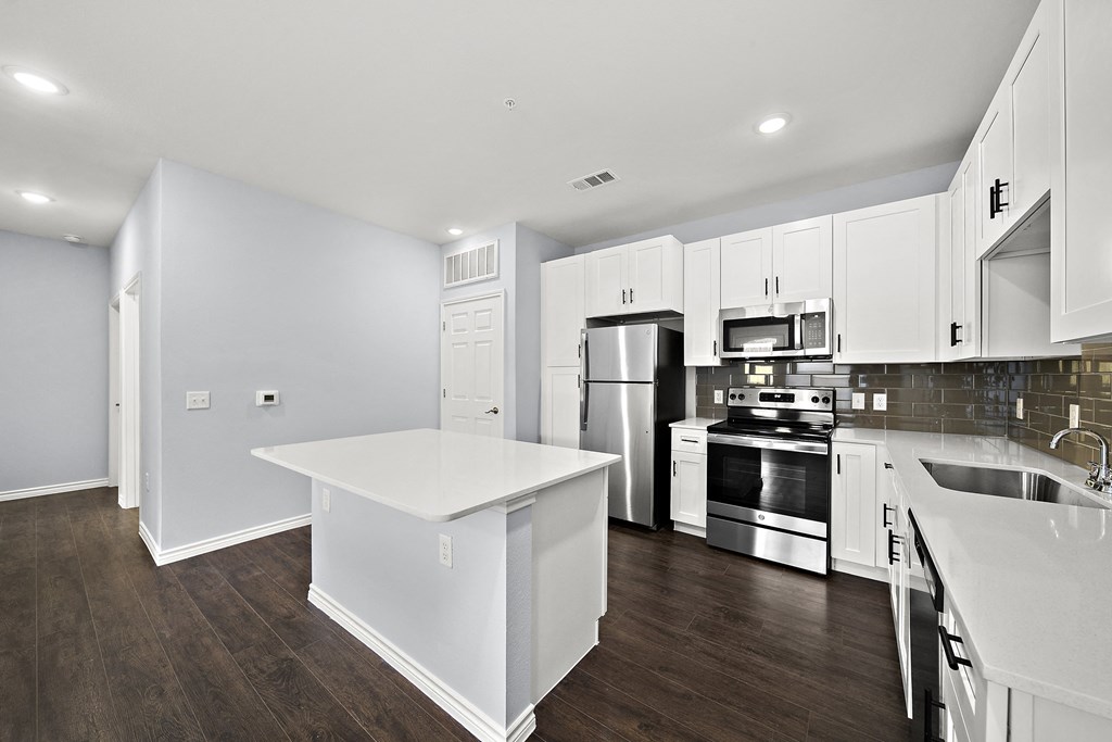 a large kitchen with white cabinets and stainless steel appliances