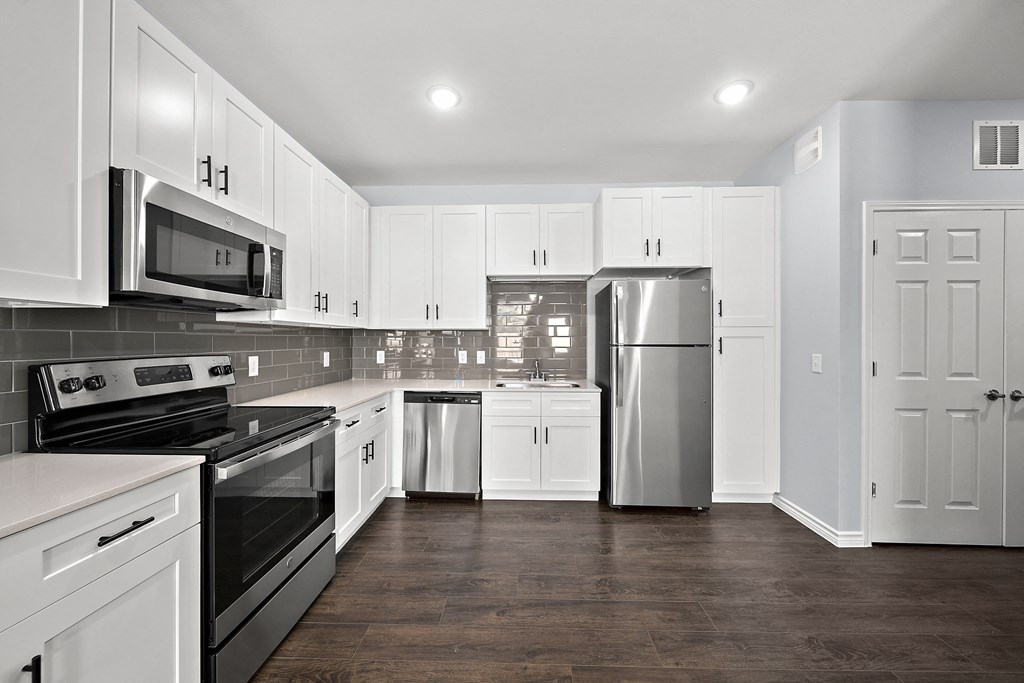 a renovated kitchen with white cabinets and stainless steel appliances