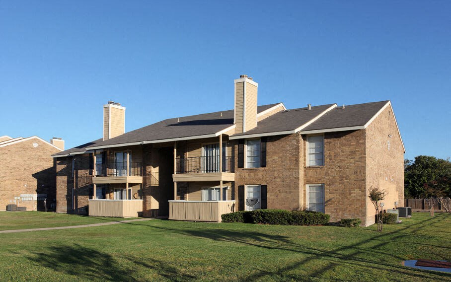 a brick apartment building with balconies and a lawn  at Wymberly Pointe, Grand Prairie, TX, 75052