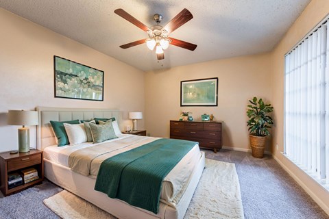 A bedroom with a large bed and a ceiling fan.