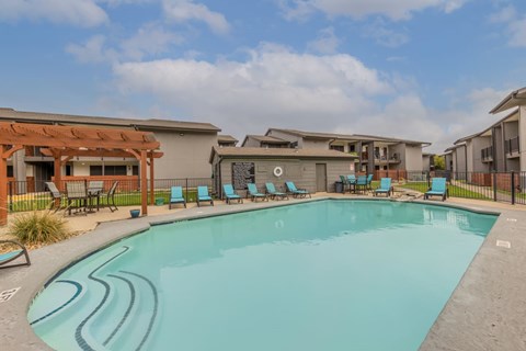 A swimming pool surrounded by lounge chairs and buildings.