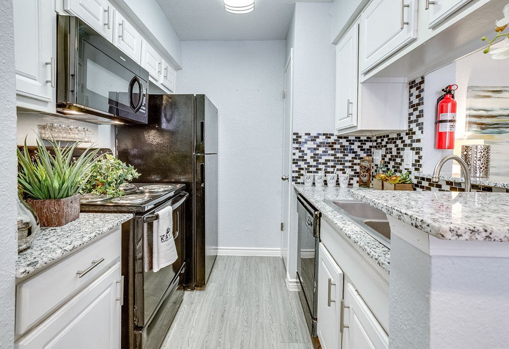 A kitchen with a black refrigerator and white cabinets.