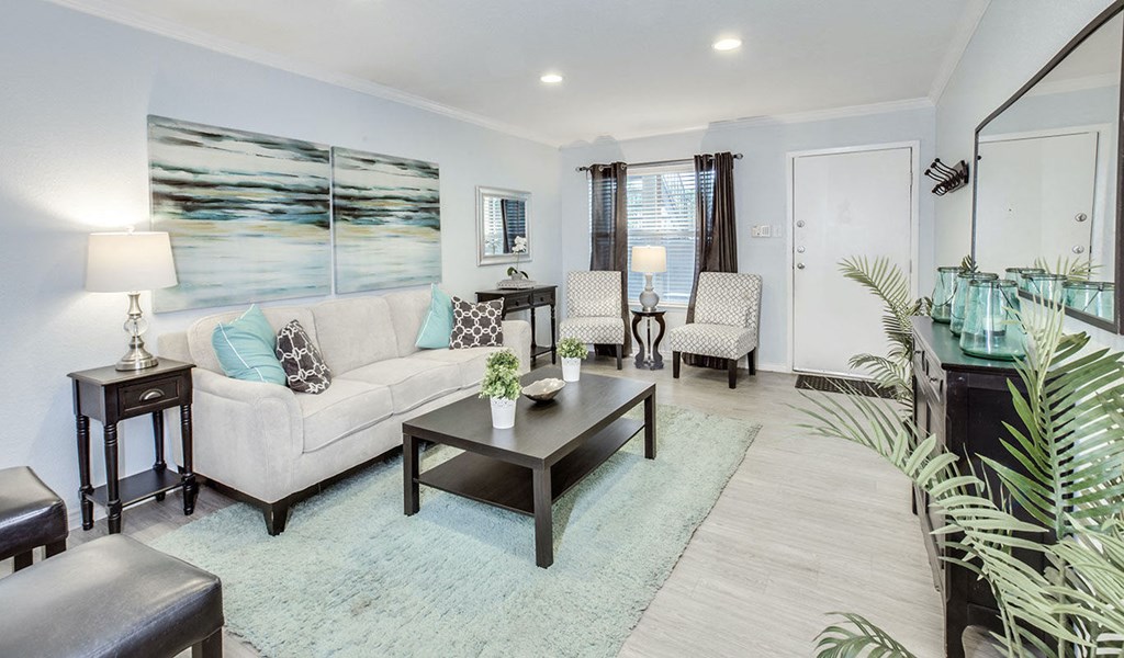 A living room with a white couch, a coffee table, and a painting on the wall.