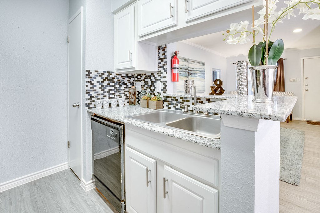 A kitchen with a white counter top and a sink.