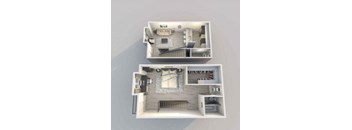 A dollhouse with two levels, one with a staircase and the other with a couch and a table.