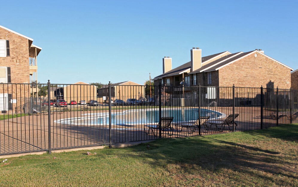a swimming pool in front of a house behind a fence  at Wymberly Pointe, Grand Prairie, 75052