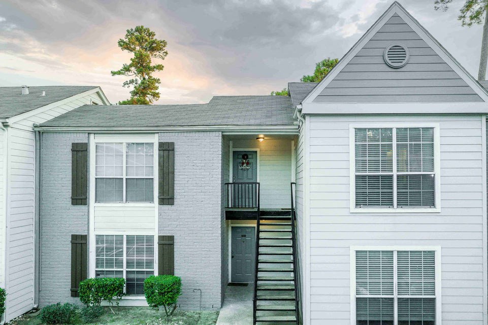 A grey house with a tree on the roof and a smaller house to the right.