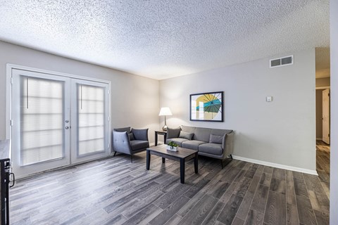 A living room with a grey couch and a painting on the wall.