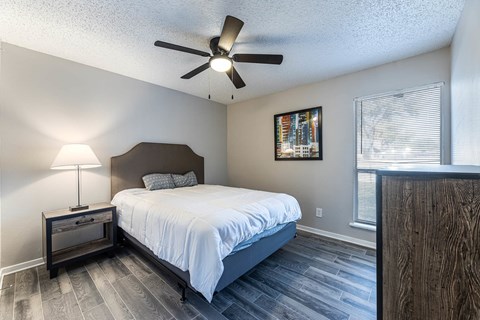 A bedroom with a bed, nightstand, and a ceiling fan.
