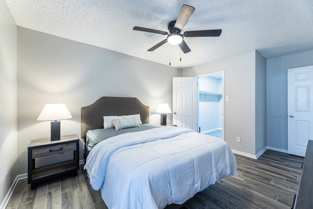 A bedroom with a bed, nightstand, and a ceiling fan.