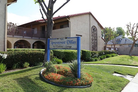 A sign for Arrowcrest Dillas stands in front of a building.