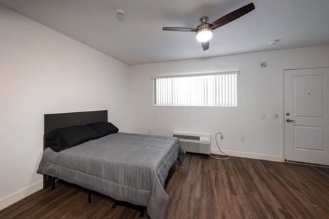 A bedroom with a bed, a ceiling fan, and a window with blinds.