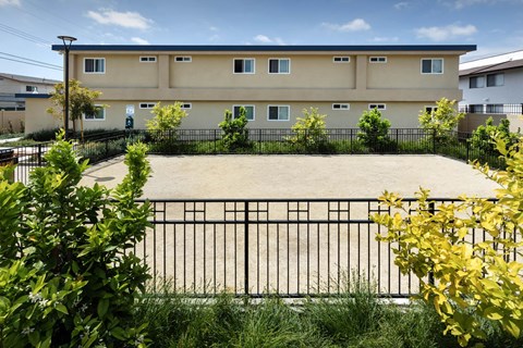 A building with a black fence and green bushes in front.