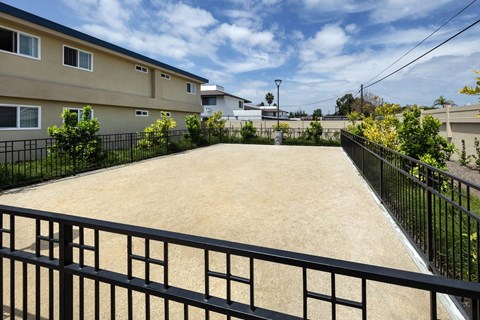 A black fence surrounds a sandy area.