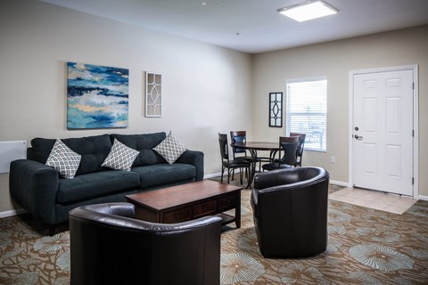 A living room with a black couch and a painting on the wall.