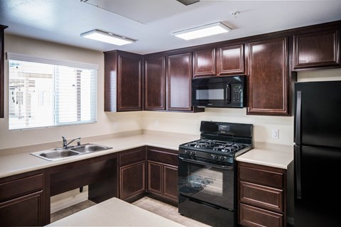 A kitchen with dark brown cabinets and black appliances.