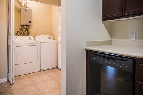A black dishwasher is in a kitchen next to a wall.