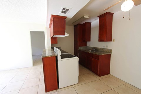 A kitchen with red cabinets and a white counter.