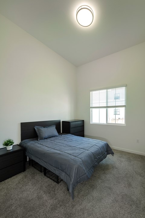A bedroom with a bed, nightstand, and window.