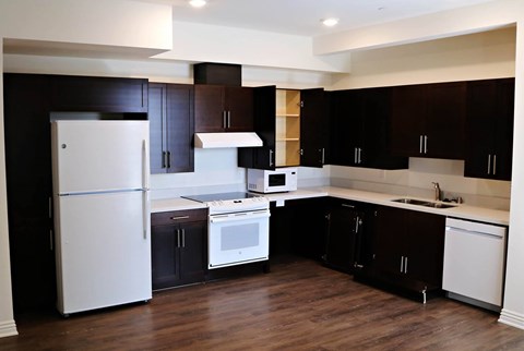 A kitchen with dark brown cabinets and white appliances.