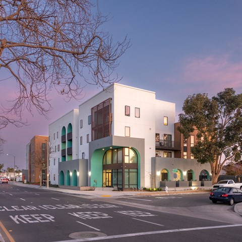 A white building with a green trim is on a street corner.