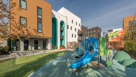 A playground with a blue slide and a green hill.