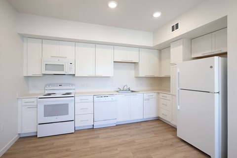 A white kitchen with a refrigerator on the right.