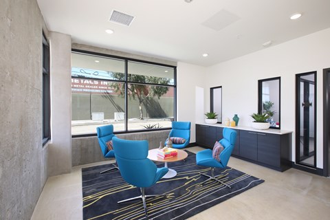 A modern living room with blue chairs and a black and white rug.