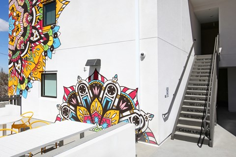 A white building with a staircase and a mural on the wall.